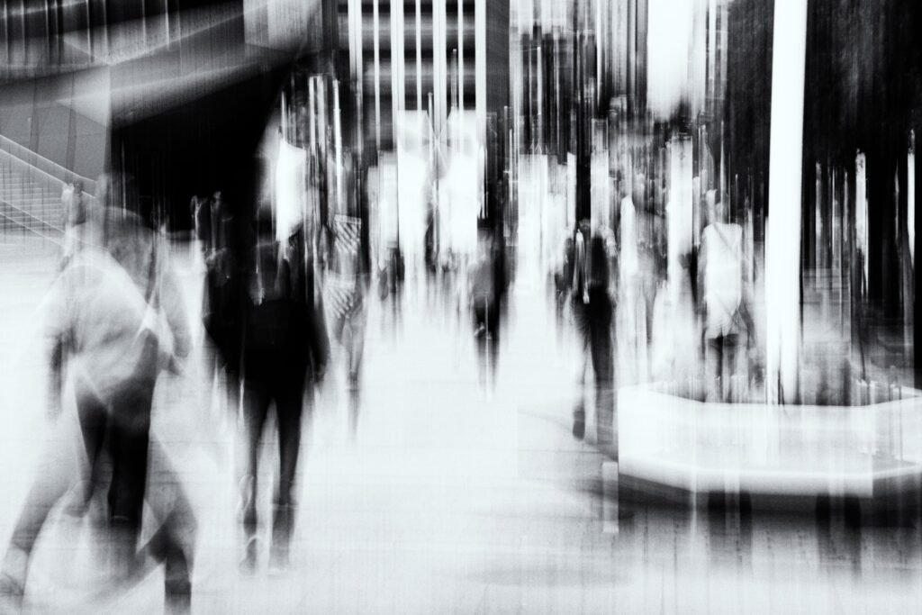 Groupe de personnes floues et formes architecturales, contraste doux, noir et blanc, effet de dissolution.