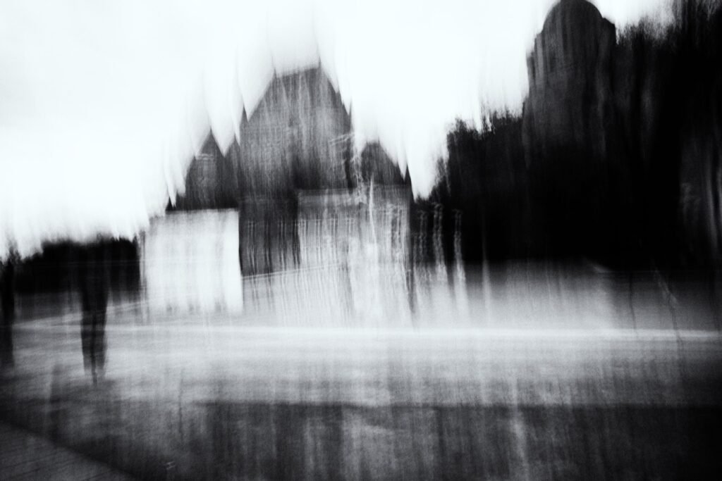 Monument sombre sous ciel clair, silhouette isolée, flou horizontal ICM en noir et blanc.